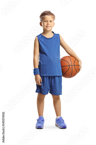 Full length portrait of a boy in a blue sports jersey holding a basketball and smiling at camera © Ljupco Smokovski