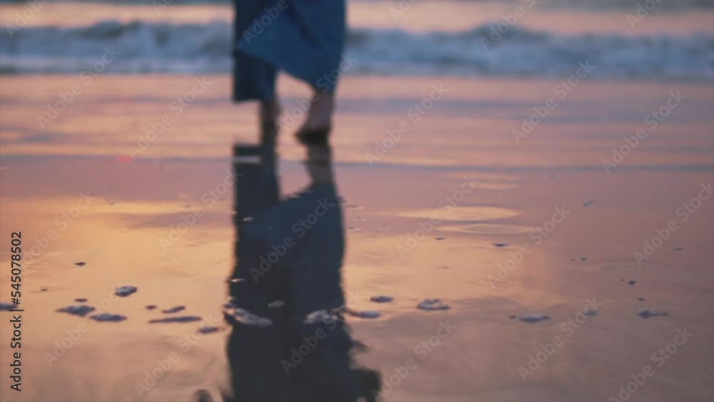 Young woman in blue pants walking alone on the beach in the sunset. Young woman in blue pants walking alone on the beach in the sunset.