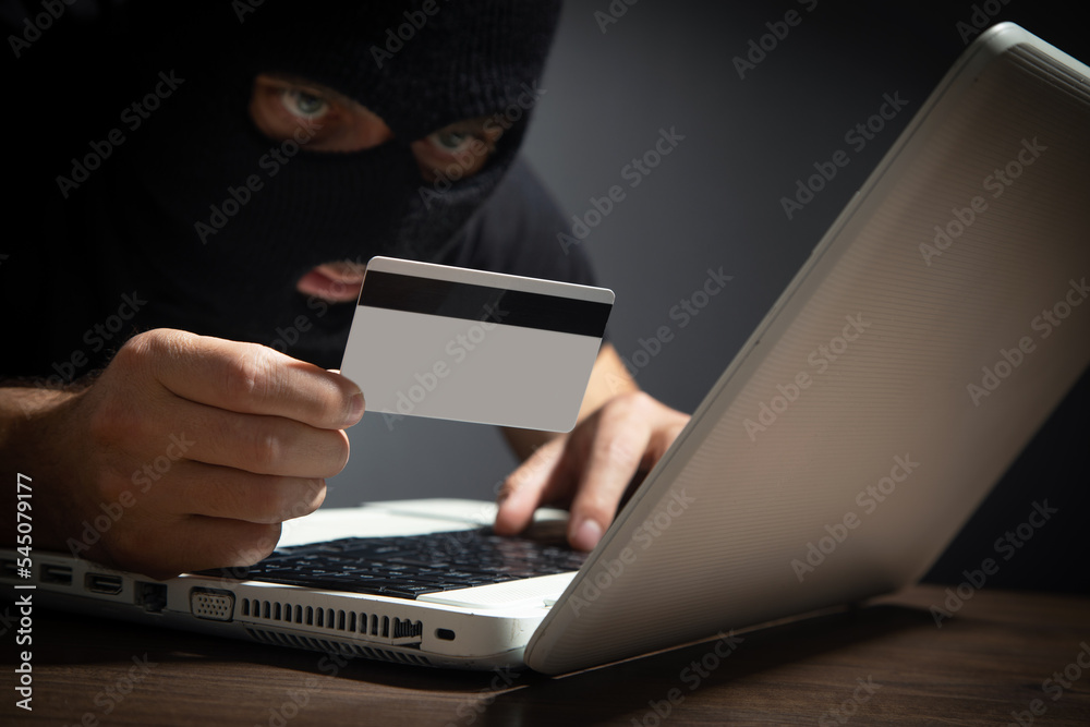 Hacker with credit card and laptop computer. Cyber crime Hacker with credit card and laptop computer. Cyber crime