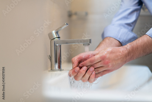 Man using soap and washing hands under the water tap. Hygiene concept hand closeup detail. 