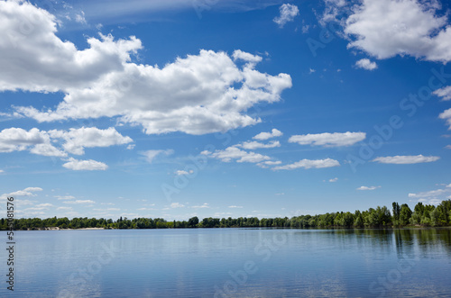 Beautiful river landscape. Lake surface on a sunny perfect day. The surface of the water against the background of trees and a blue sky. Blurred image  selective focus