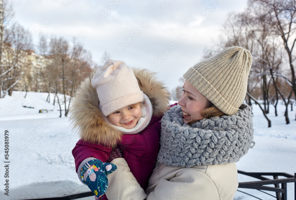 Mother and daughter are walking in the winter city park on Christmas and New Year holidays. Parent and little child having fun outdoors Mother and daughter are walking in the winter city park on Christmas and New Year holidays. Parent and little child having fun outdoors