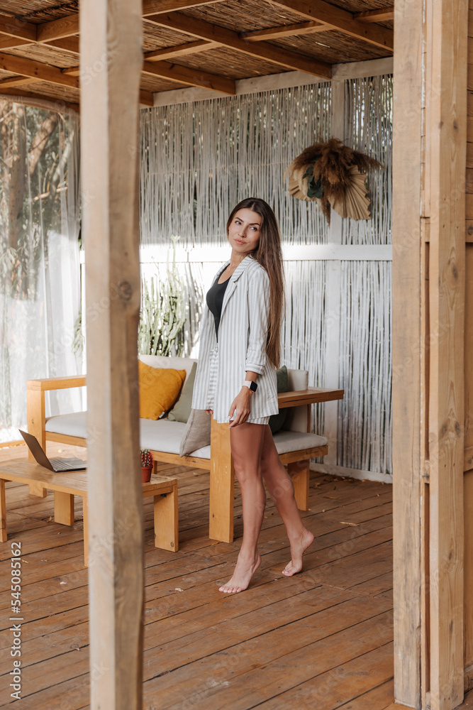 beautiful brunette woman with long hair in a white jacket resting in a bungalow