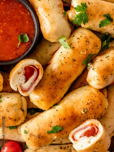 Close-up of the homemade oven-baked pizza sticks with tomato sauce top view with fresh parsley sprinkled, top view