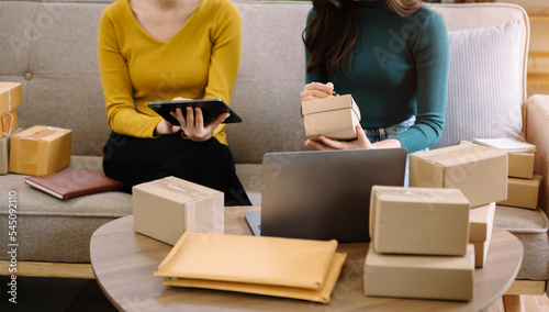 young Asian wman and women at office of their business online shopping.In home office. photo