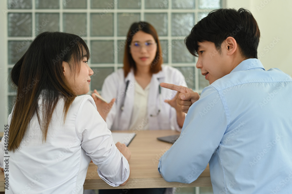 Back view of young couple arguing during family therapy counselling session with psychologist in clinic Back view of young couple arguing during family therapy counselling session with psychologist in clinic