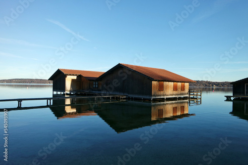 calm and reflecting lake with boat house and with blue water and blue sky. lake Starnberg. bavaria