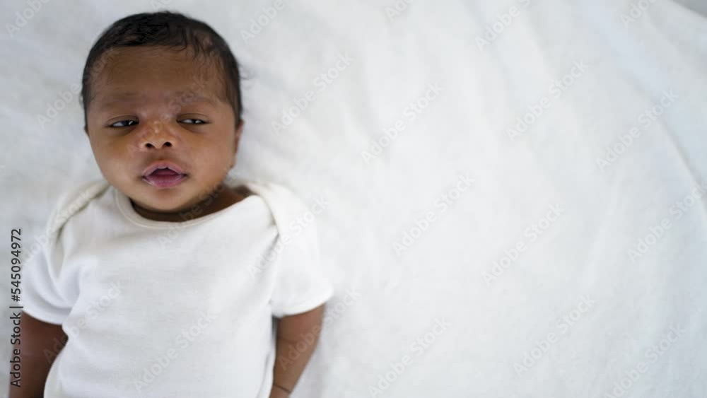 Closeup portrait of african happy baby lying play on bed over white background with copy space. Healthy newborn child take a nap asleep. Family love newborn healthcare medical concept. Closeup portrait of african happy baby lying play on bed over white background with copy space. Healthy newborn child take a nap asleep. Family love newborn healthcare medical concept.