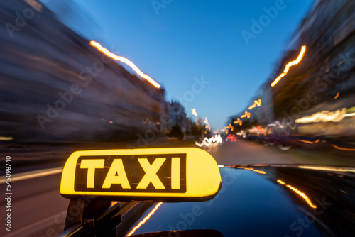 Fototapete Illuminated taxi sign on moving car roof at night