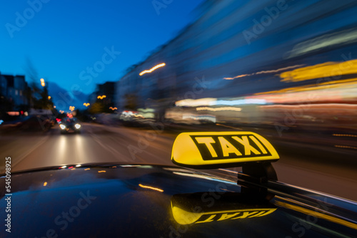 Illuminated taxi sign on moving car roof at night