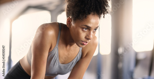 Gym, training and tired black woman breathing after exercise, workout and sports fitness. Woman in a health and wellness club breathe and relax after intense athlete challenge with focus