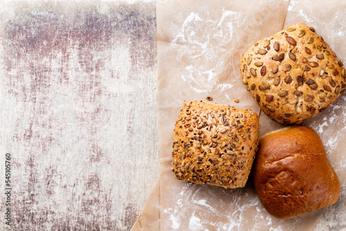 Gold rustic crusty loaves of bread and buns on wooden background. Still life captured from above top view, flat lay.