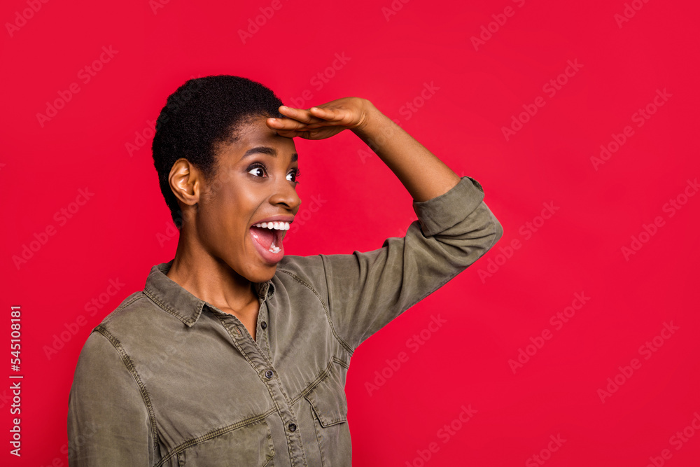 Portrait of attractive cheerful amazed girl looking far away copy blank space isolated over bright red color background