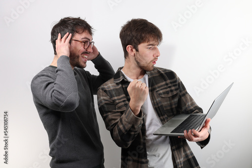 deux amis ou collègues sont debout avec un ordinateur portable. Ils serrent le poing en signe de réussite ou de victoire photo