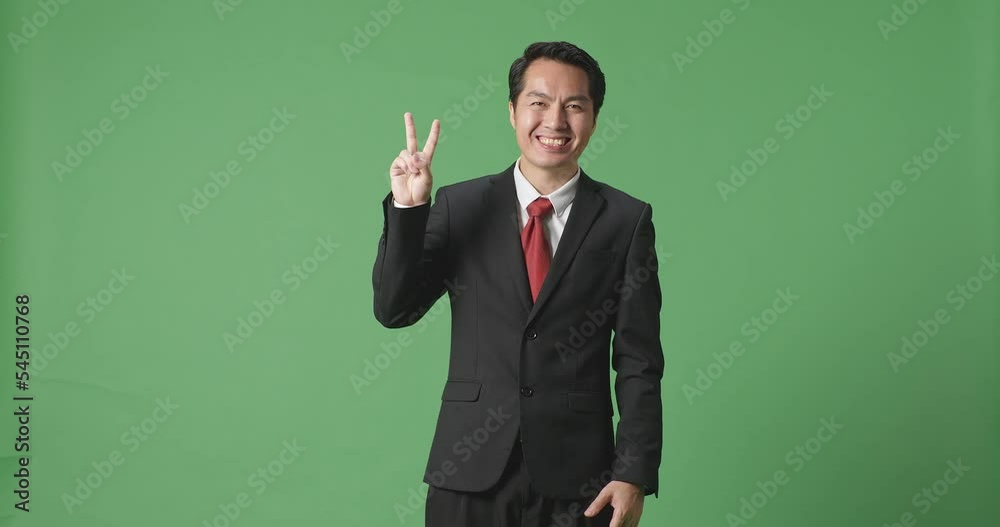An Asian Business Man Showing Gesture Peace And Smiling While Standing On Green Screen In The Studio
An Asian Business Man Showing Gesture Peace And Smiling While Standing On Green Screen In The Studio