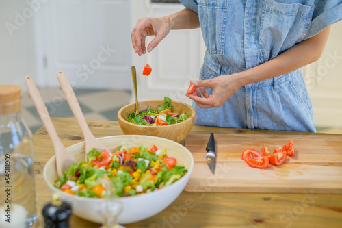 Crop woman preparing healthy salad in kitchen