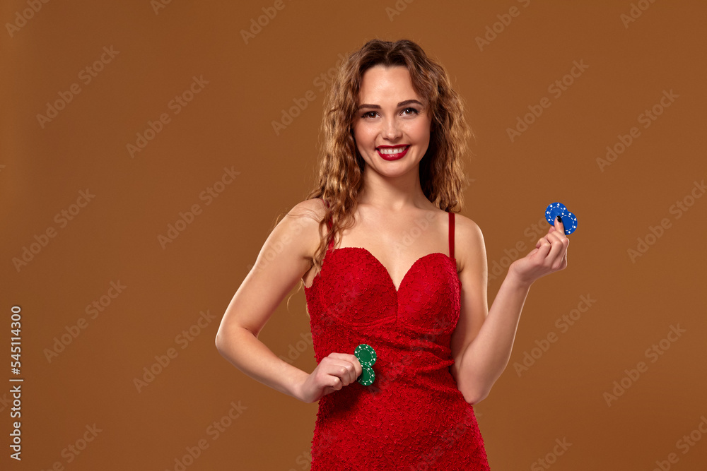 Casino concept. Portrait of young brown-haired caucasian woman, playing in casino. Roulette, poker chips, cards, wheel, brown background Casino concept. Portrait of young brown-haired caucasian woman, playing in casino. Roulette, poker chips, cards, wheel, brown background