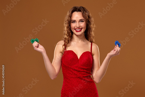 Casino concept. Portrait of young brown-haired caucasian woman, playing in casino. Roulette, poker chips, cards, wheel, brown background photo