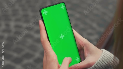 Beautiful Woman using Chroma Key Smartphone outside City Street . Female Using Green Screen Mobile Phone. Over the Shoulder Static Medium Close-up Shot
