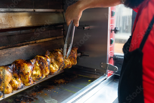 Chef of the kebab restaurant, with a metal tool controlling the chicken grill