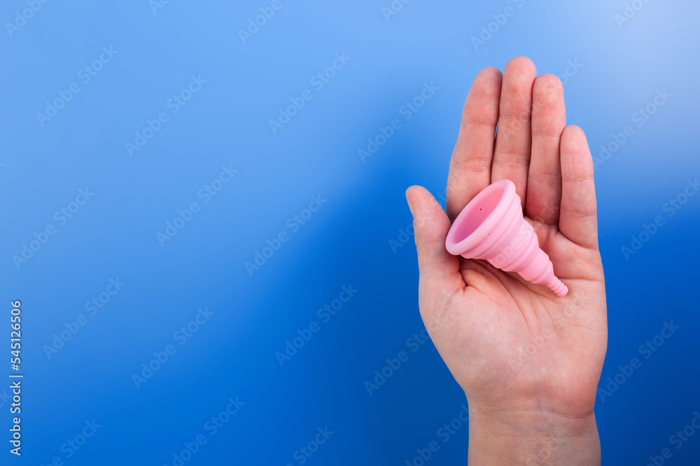 Close up view of woman holding pink menstrual cup isolated over violet background, woman's period, menstrual cup in hands, modern methods for crytical days. Gynecology and hygiene products concept. Close up view of woman holding pink menstrual cup isolated over violet background, woman's period, menstrual cup in hands, modern methods for crytical days. Gynecology and hygiene products concept.