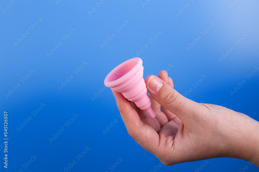 Close up view of woman holding pink menstrual cup isolated over violet background, woman's period, menstrual cup in hands, modern methods for crytical days. Gynecology and hygiene products concept.