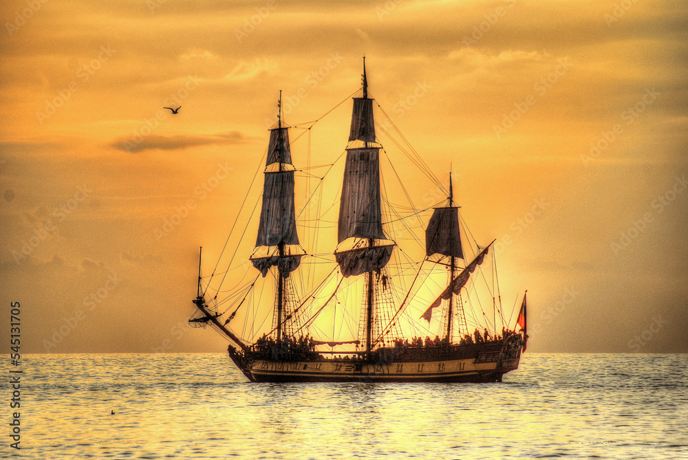 Sunset over the sea. Soft orange sunlight. Romantic sea background with sailing ship.