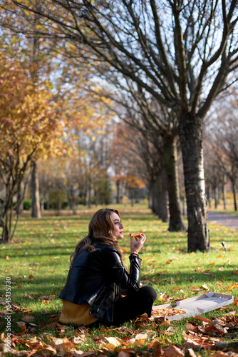 Young girl eats pizza in the park enjoying autumn nature..