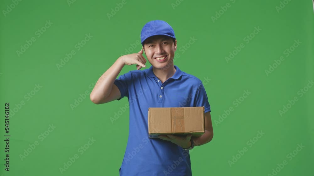 Asian Male Courier In Blue Uniform Showing Call Me Gesture And Smiling While Delivering A Carton On Green Screen Background In The Studio
Asian Male Courier In Blue Uniform Showing Call Me Gesture And Smiling While Delivering A Carton On Green Screen Background In The Studio
