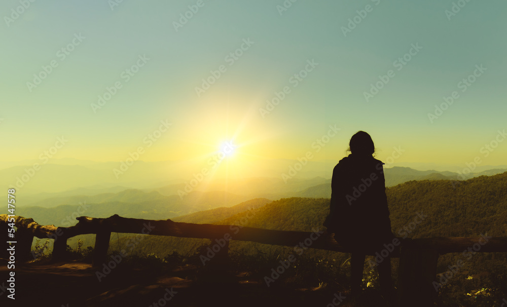 Silhouette of woman sitting alone looking at watching sunset on mountain, Doi Pui ViewPoint in Chiang Mai, Thailand Silhouette of woman sitting alone looking at watching sunset on mountain, Doi Pui ViewPoint in Chiang Mai, Thailand