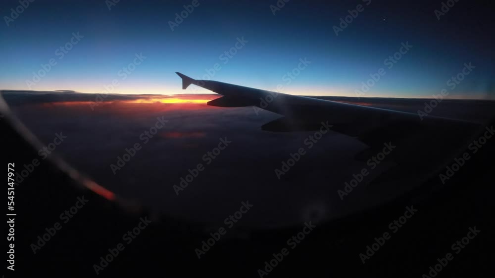 Morning view of the sunrise through the window during the airplane flight. The plane wing among the clouds Morning view of the sunrise through the window during the airplane flight. The plane wing among the clouds