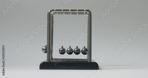 Close-up of driving a simple Newton's cradle. Kinetic pendulum. Chromatic metal balls wobble and slow down. Moving something, inertia concept, science, physics lesson. Psychological hypnosis session photo