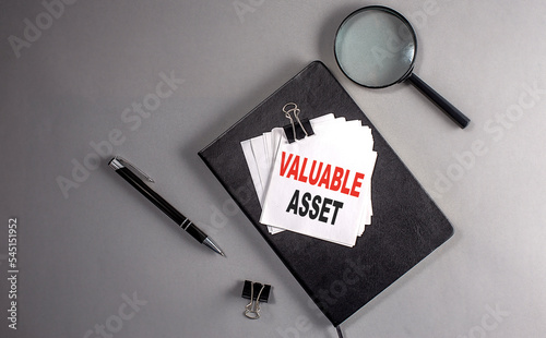 VALUABLE ASSET Text on a sticky on black notebook , business concept photo