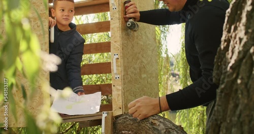 happy father and son building a tree house in the garden
