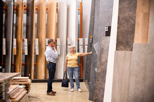 Woman talking to senior man while shopping laminated boards at hardware store photo