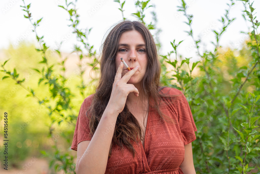 Happy young woman smoking in the countryside Happy young woman smoking in the countryside