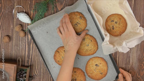 Female hand takes oatmeal coockies from tray and puts it into the Christmas box photo