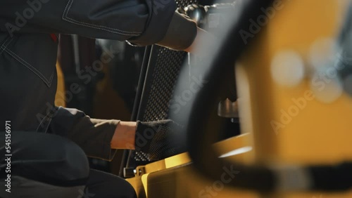 Tilt down slowmo of female mechanic in hard hat and coverall using special crank bolt wrench to fix bulldozer machine at industrial plant