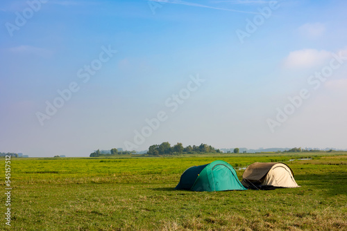 Adventure activities background, small tent in green grass under morning sunlight, copy space for text.