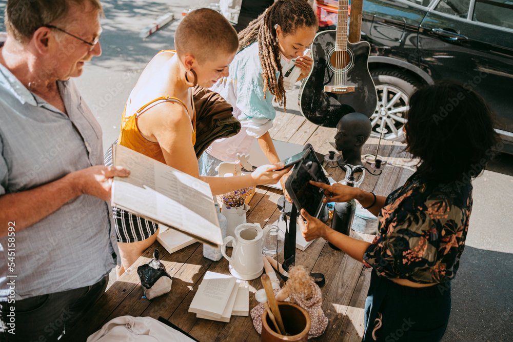 High angle view of owner processing online payment of female customer at flea market