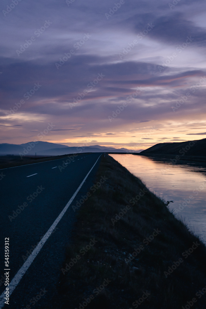 Road in mountainside with river at dusk in rural area