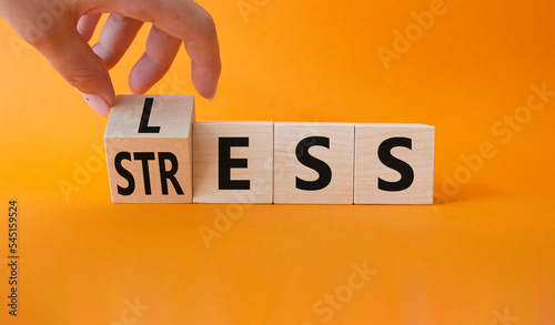 Less Stress symbol. Doctor hand turns wooden cube and changes word Stress to Less. Beautiful orange background. Medicine and Less Stress concept. Copy space