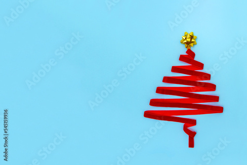 Christmas tree made from ribbon with golden star shape bow isolated on blue pastel background.