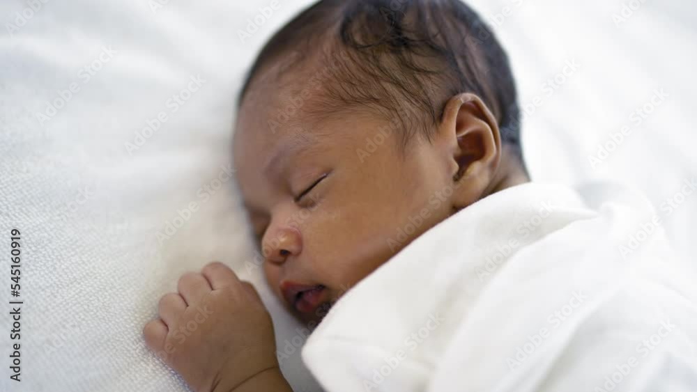 Closeup portrait of african happy baby sleeping sweet dream on bed over white background with copy space. Healthy newborn child take a nap asleep. Family love newborn healthcare medical concept.