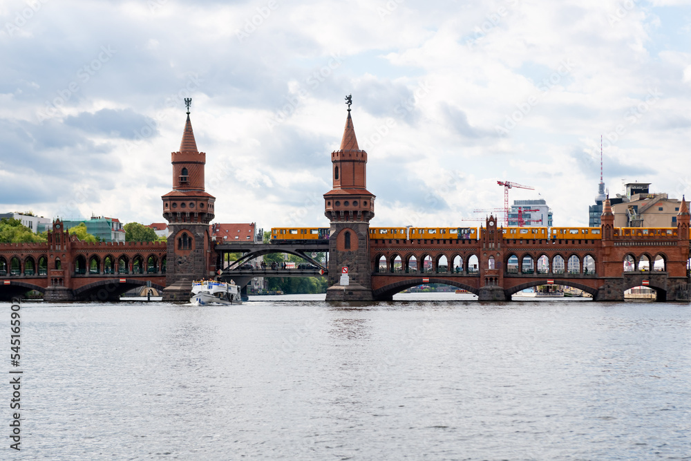 Oberbaum bridge with yellow tram in Berlin seen from the water.