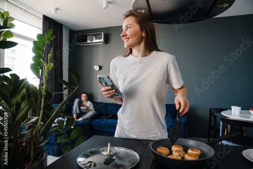 Bild auf Leinwand White young woman cooking breakfast while spending time with boyfriend