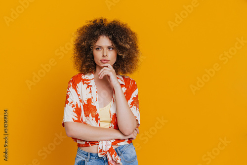 Young beautiful thoughtful curly woman with folded arms touching chin