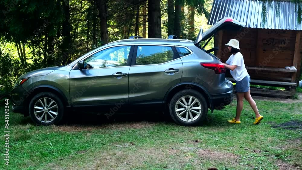 woman take out from the car trunk stuff at camping site woman take out from the car trunk stuff at camping site
