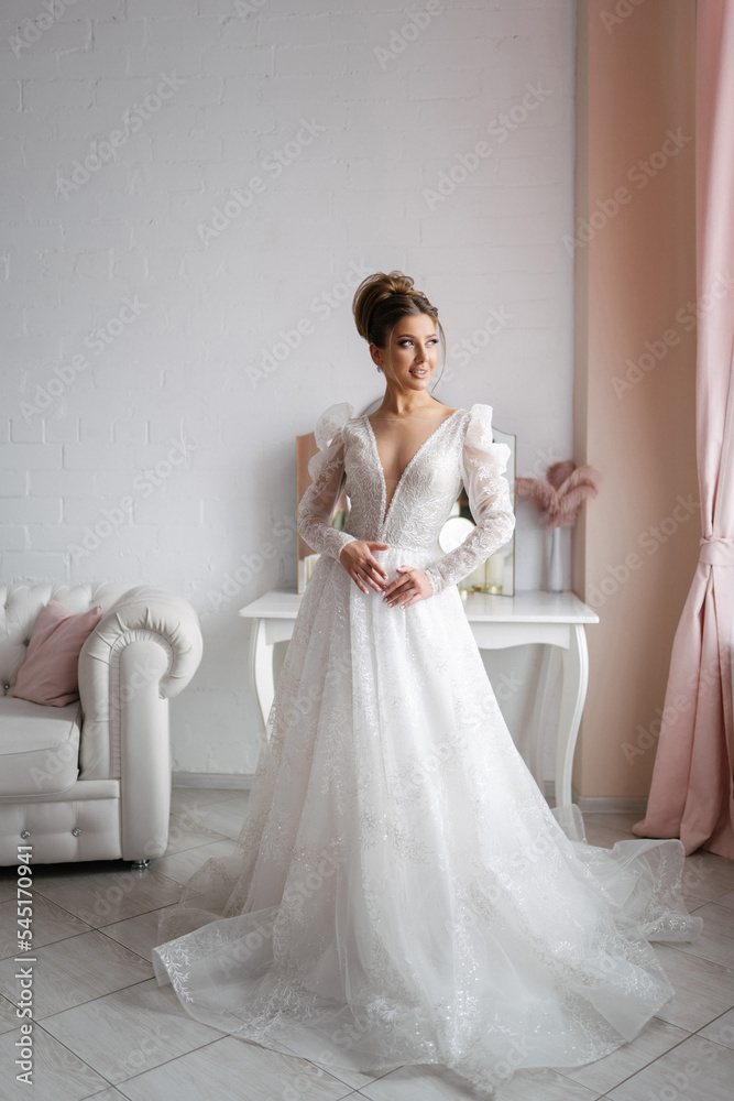 young bride in a white wedding dress posing in a light interior, full length photo, brown hair, professional makeup and hairstyle, photo for a wedding salon or agency young bride in a white wedding dress posing in a light interior, full length photo, brown hair, professional makeup and hairstyle, photo for a wedding salon or agency