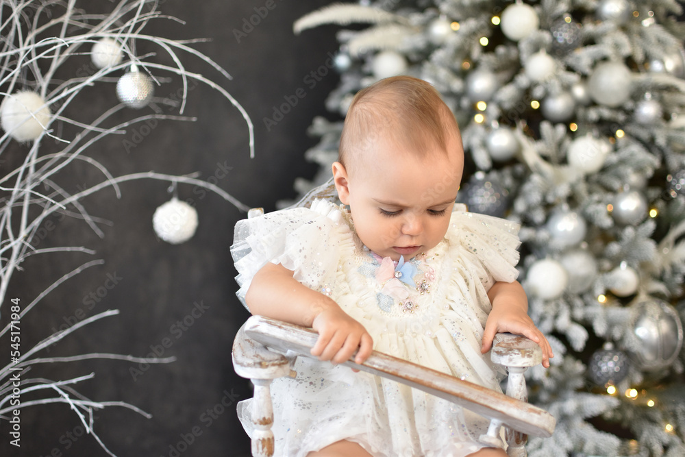 Naklejka premium Cute little baby against blurred lights on dark background. Christmas celebration